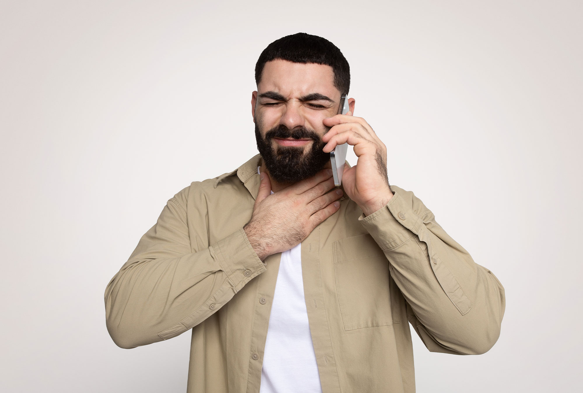 Mann am Handy hält sich schmerzverzerrt den Hals Stimm- und Sprachstörungen