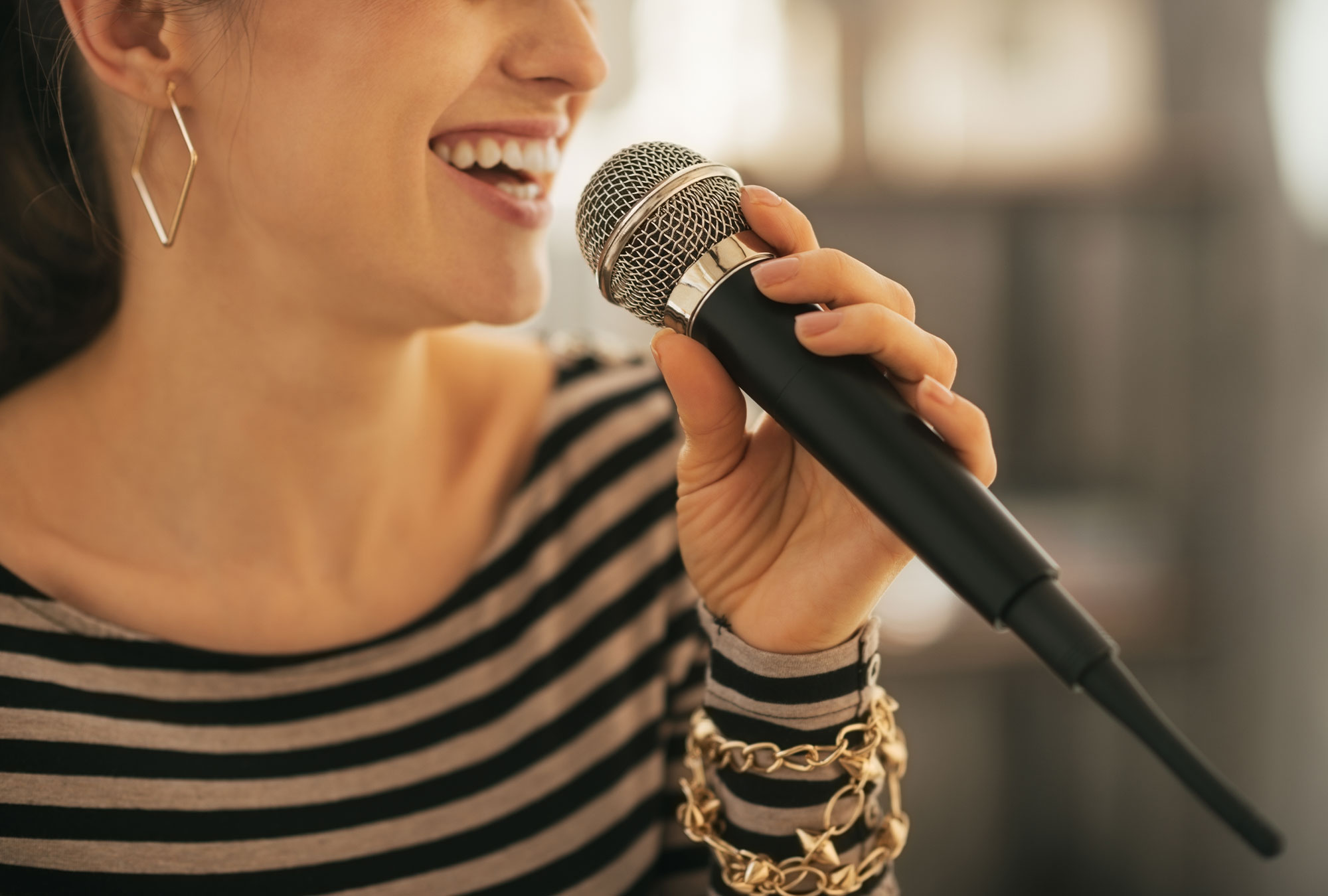Frau singt in ein Mikrofon Stimm- und Sprachstörungen